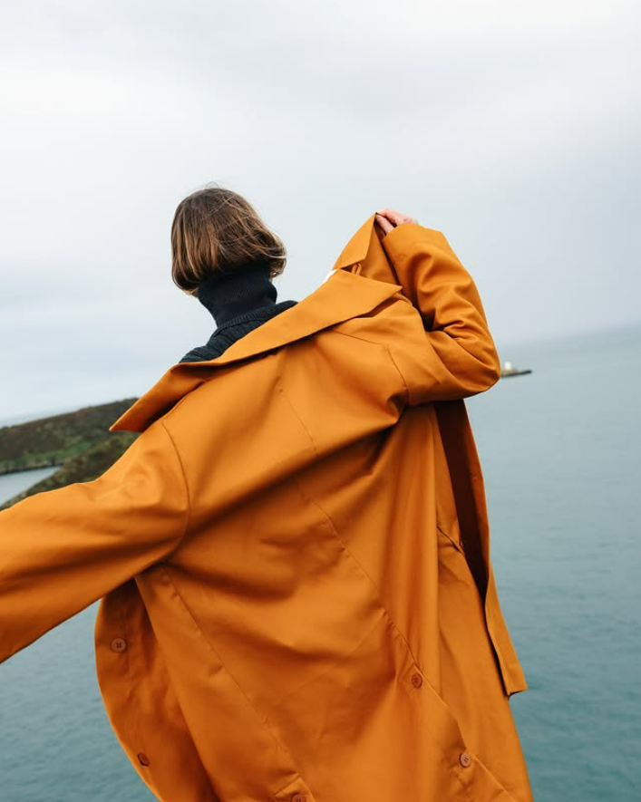 Modèle de dos en imper orange du Studio De Lostanges.